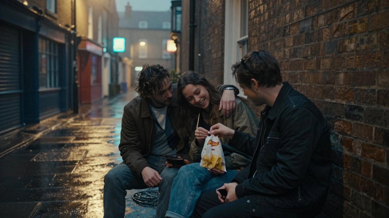 Friends sharing chips on a bench after midnight in a rainy London alley, relaxed and happy.